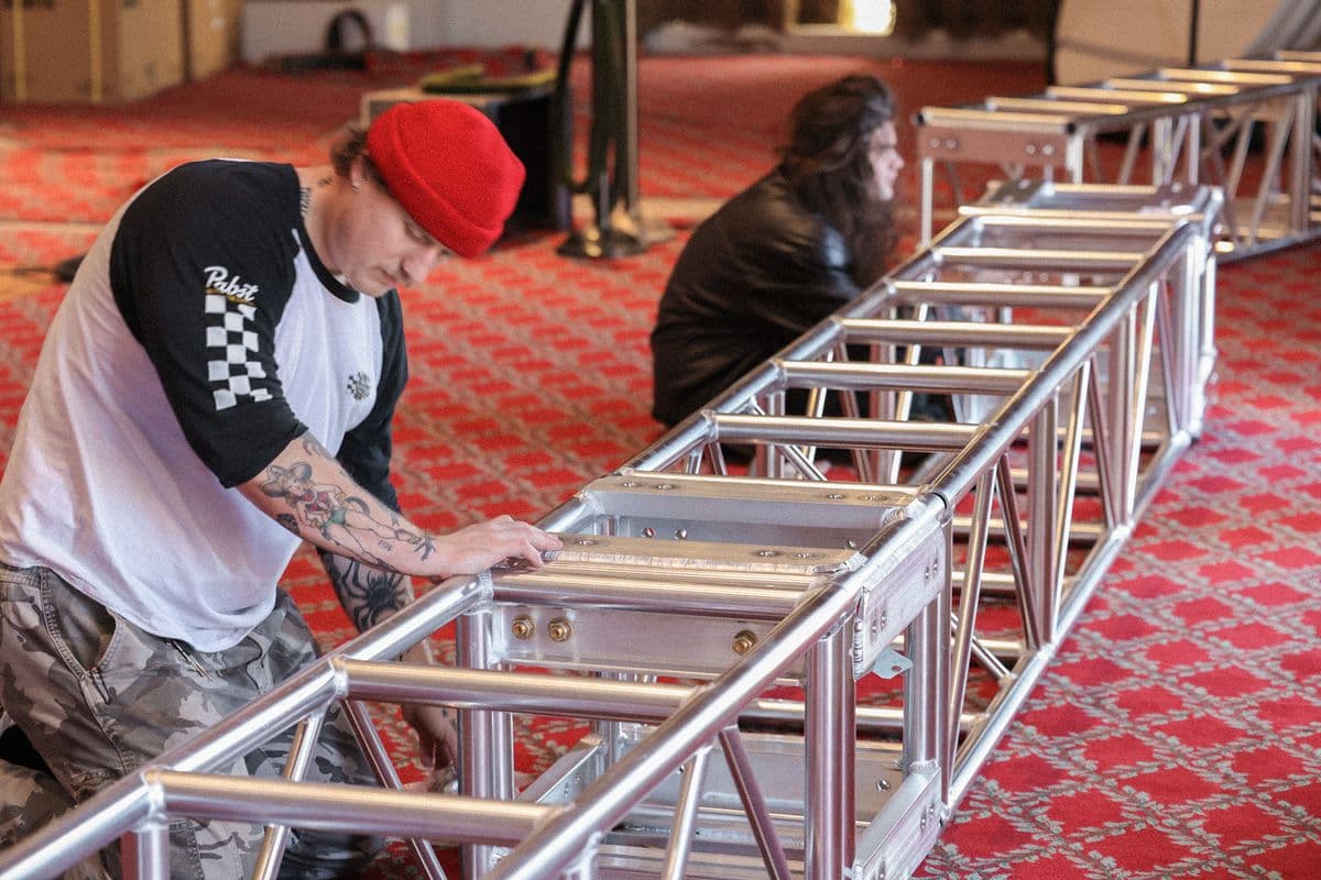 Crew assembling a long aluminum truss run for a ballroom install