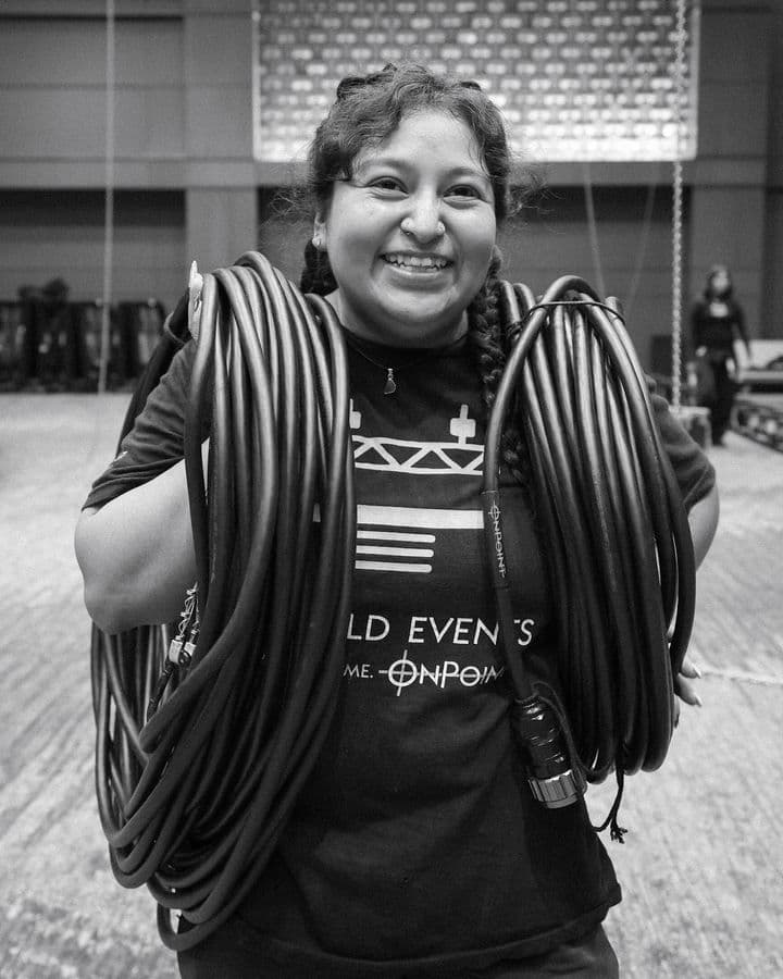 OnPoint crew member carrying coiled cable across a venue floor