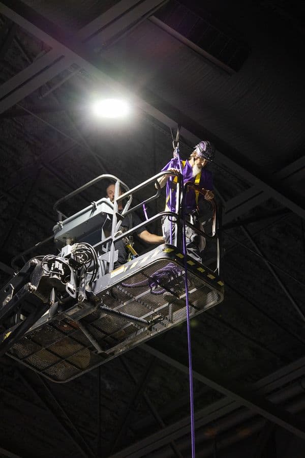 OnPoint rigger working from a personnel lift in a venue's overhead steel