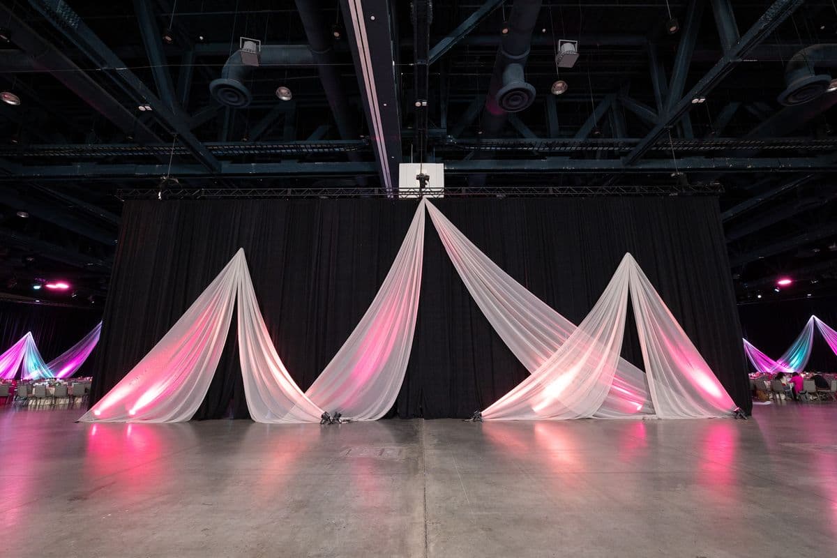 Drape wall and stage lit in pink and white for an evening event