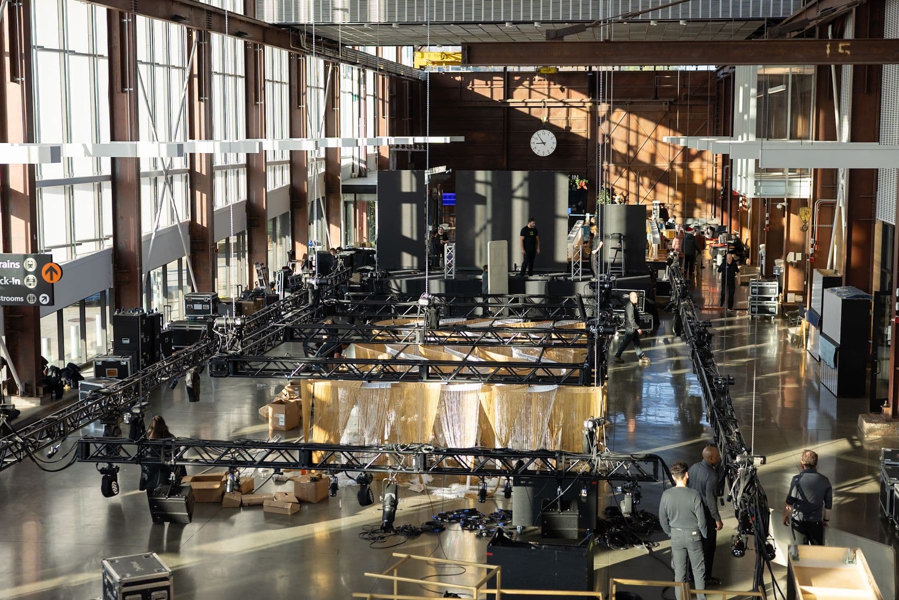 Large truss and lighting rig suspended above a glass atrium concourse